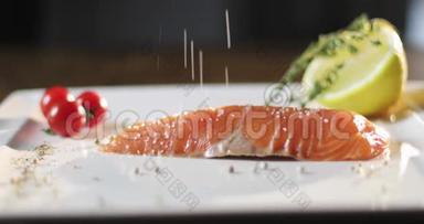厨师手里拿着手套把一条红鱼放在<strong>一个</strong>盘子里，上面放着柠檬和<strong>樱桃</strong>番茄